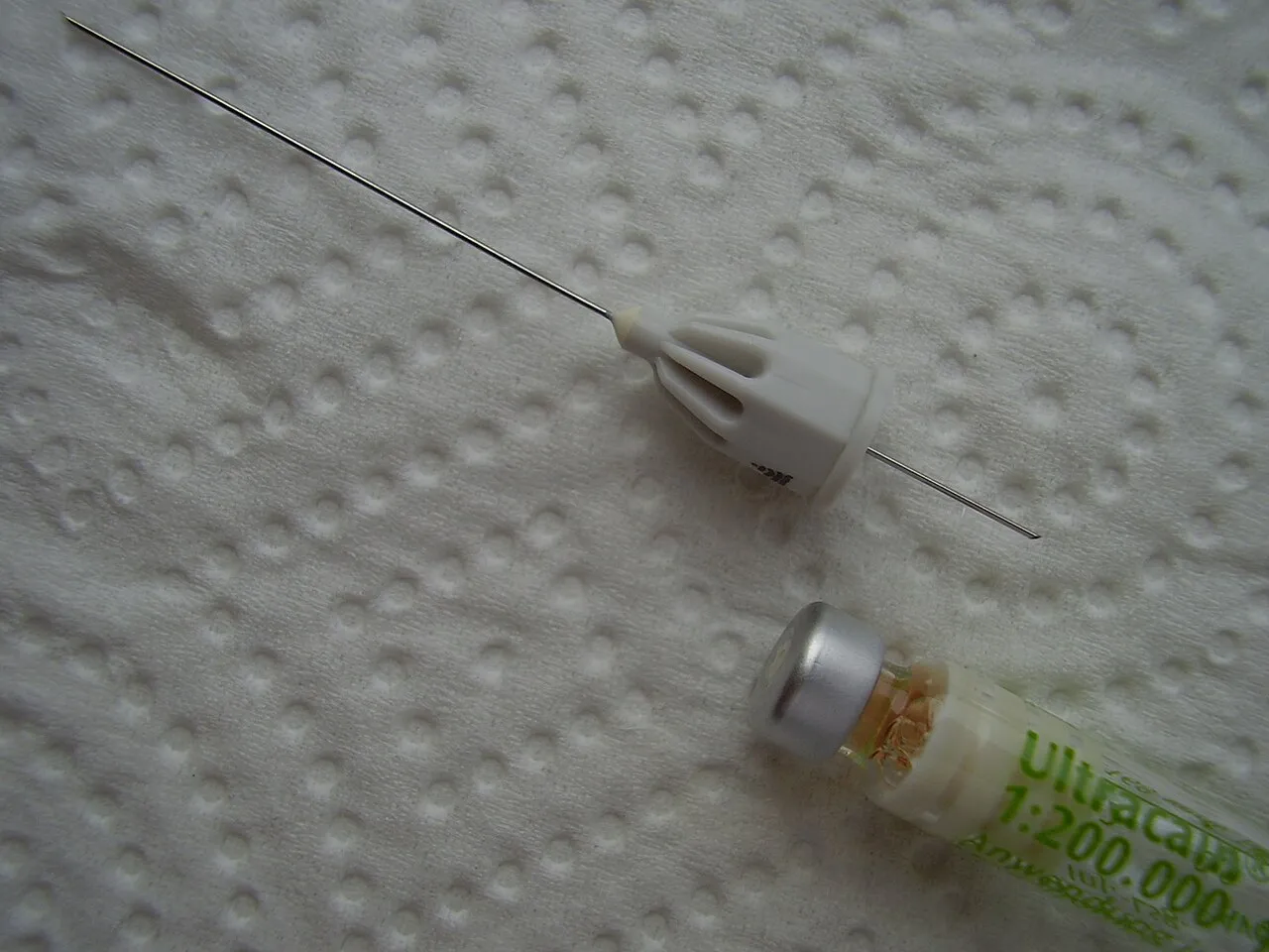 An articaine cartridge labeled 1:200,000 epinephrine (Ultracain) beside a partly capped dental needle