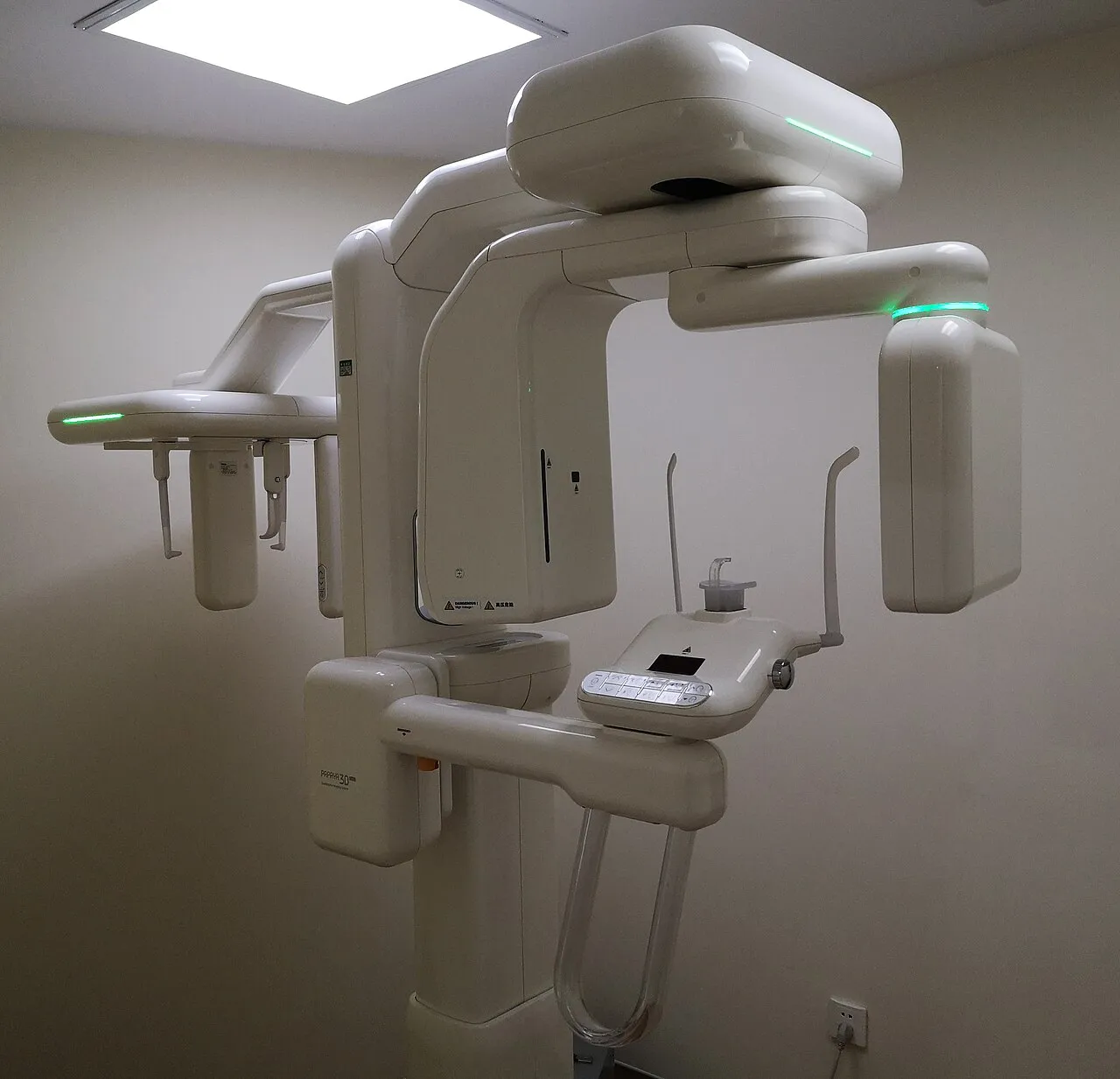 A cone beam CT unit with its rotating arm and patient positioning supports in a dental office