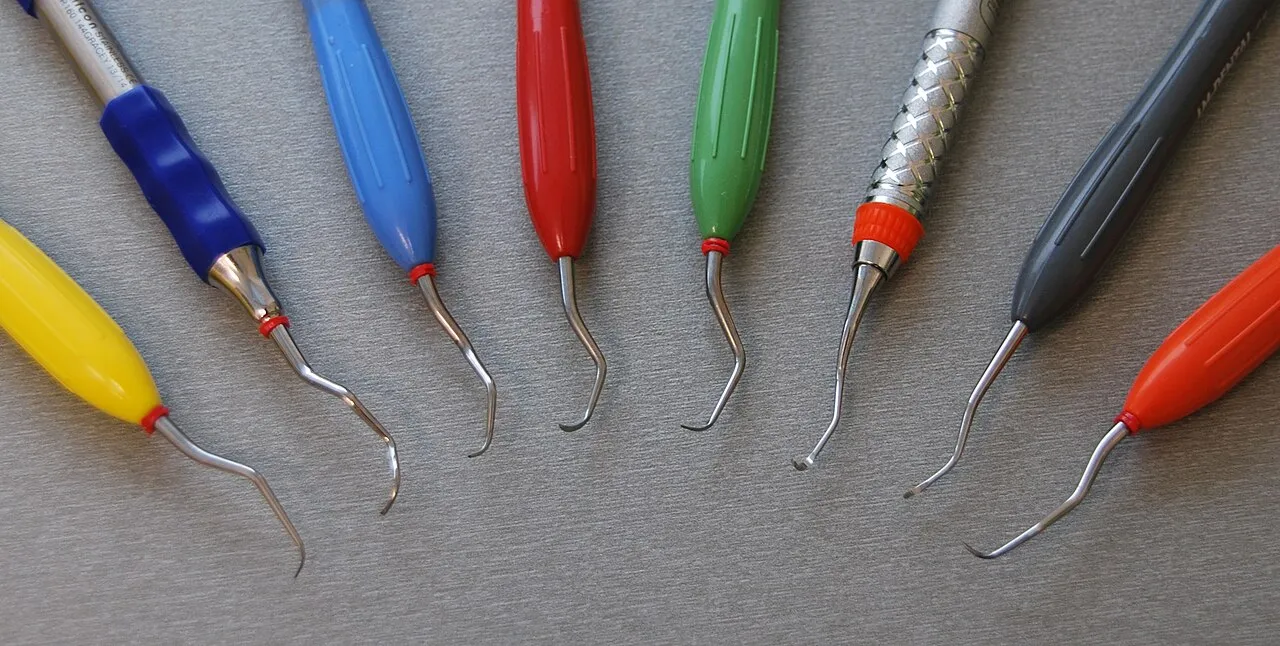 Eight curettes with colored handles fanned out, showing curved blades with rounded toes on shanks bent at different angles