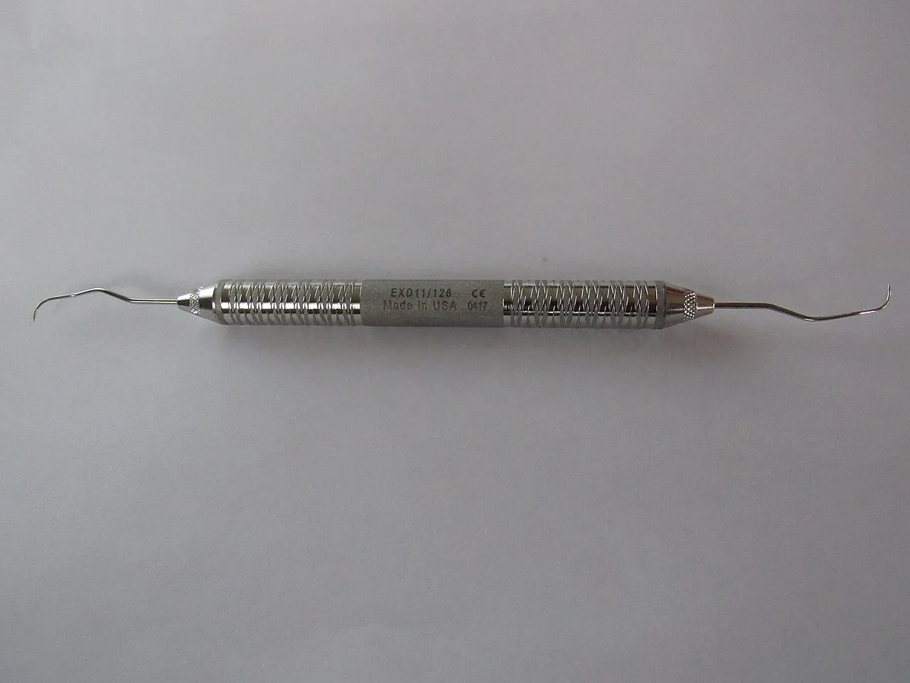 A double-ended ODU 11/12 explorer, stamped EXD11/12 on its textured handle, with a fine curved working end at each end