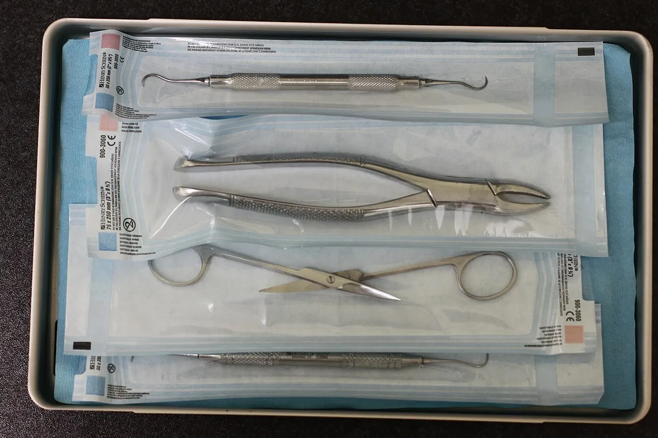 A standard instrument tray holding examination instruments inside a sterilization wrap