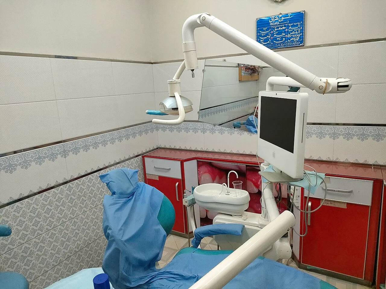 A dental chair, light and unit covered with blue plastic barriers in a clinic operatory