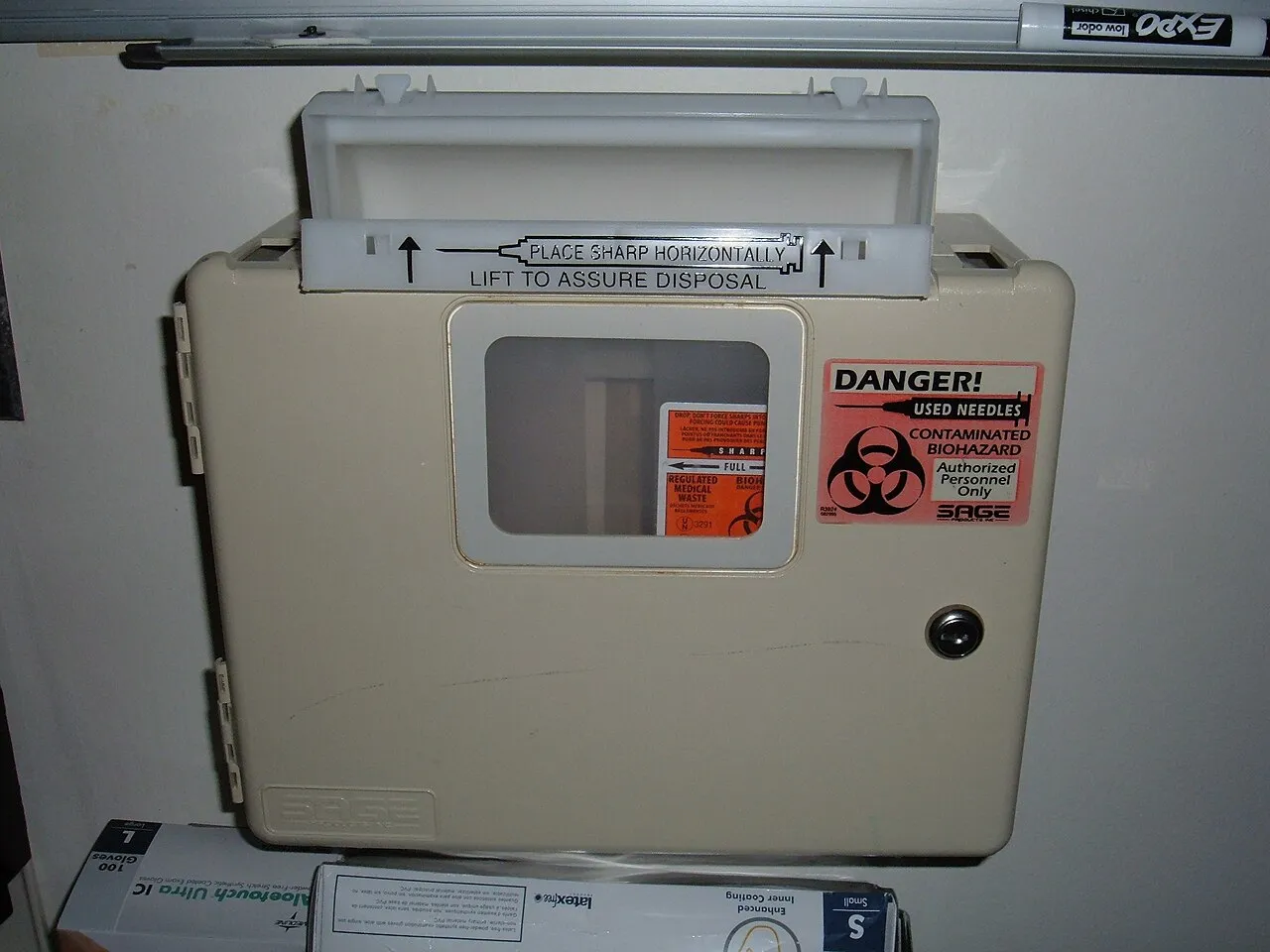 A wall-mounted sharps container in a clinic room