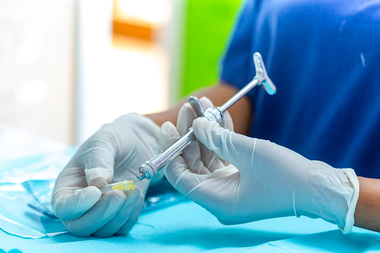 Gloved hands holding a loaded dental anesthetic syringe